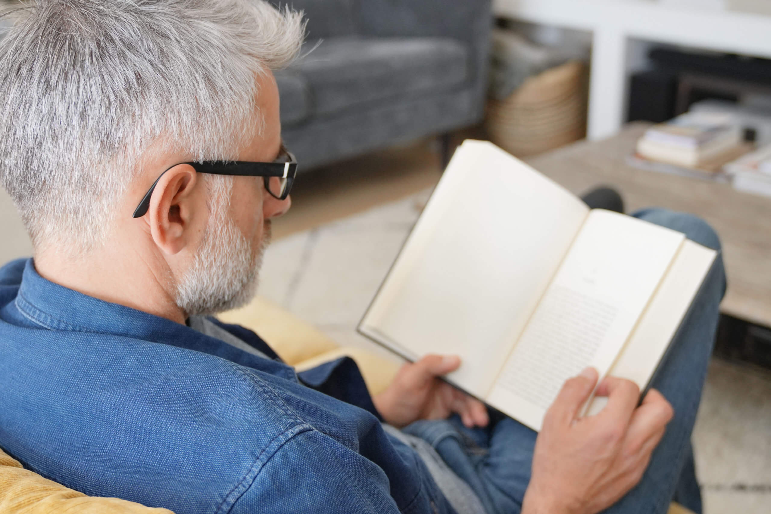 Man in 40s reading book in modern home