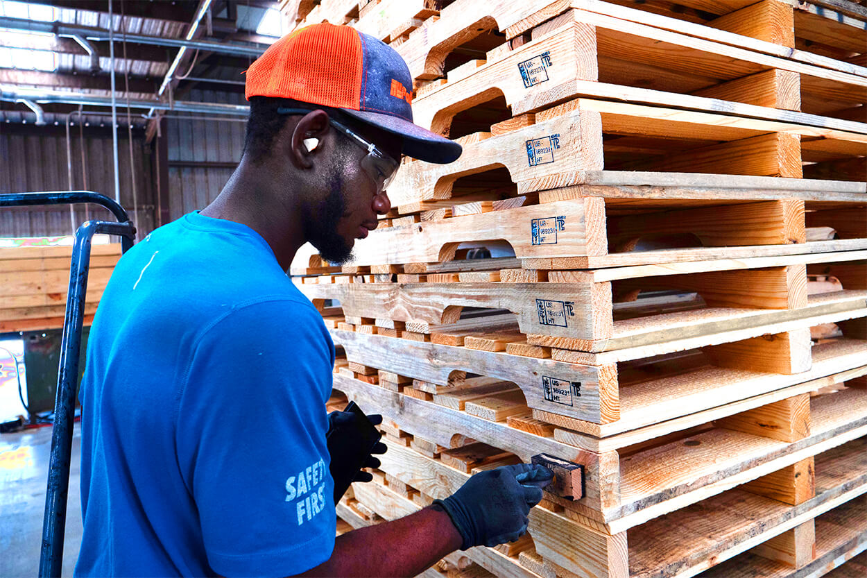 A PalletOne team member applies a stamp to heat-treated pallets.