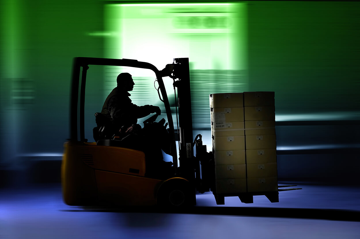 A forklift operator moves a pallet of boxes.